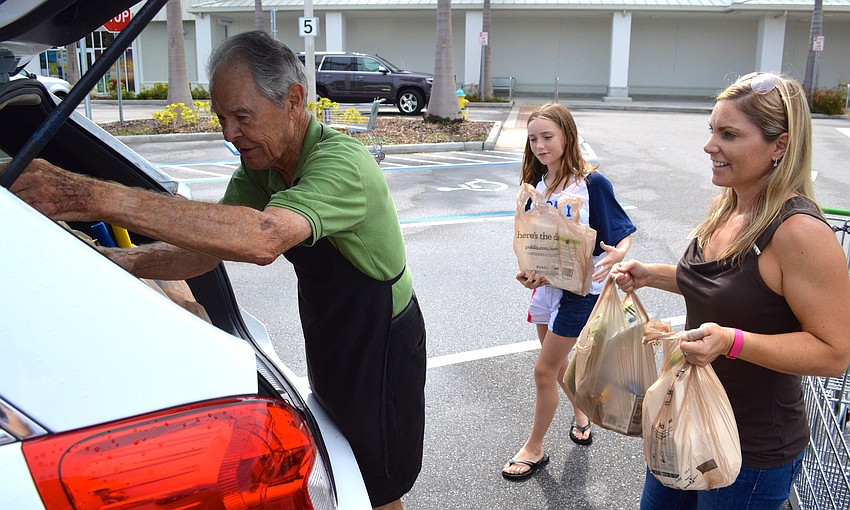 Clint Bohon helps Grace Hamilton and her mother, Julie, load groceries into the trunk of their vehicle. 