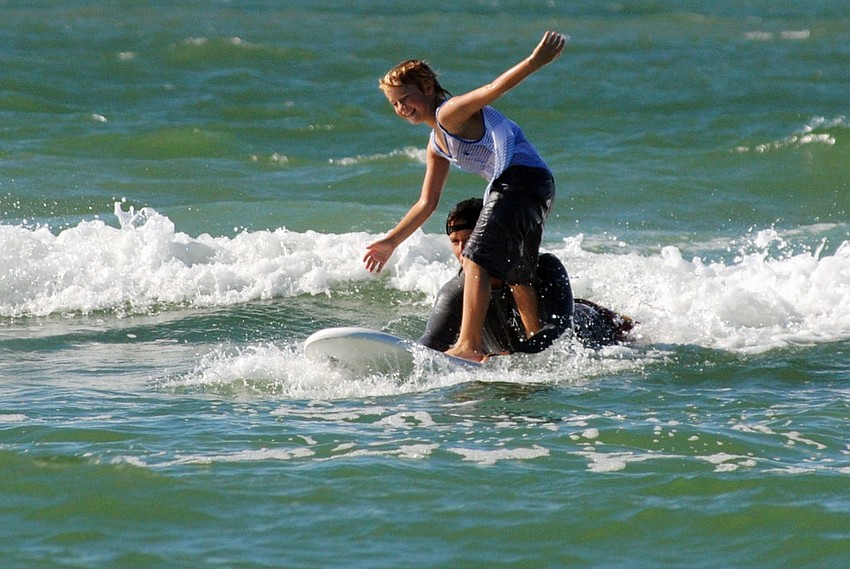 Nick Penker catches a wave with the help of Jacob Shields