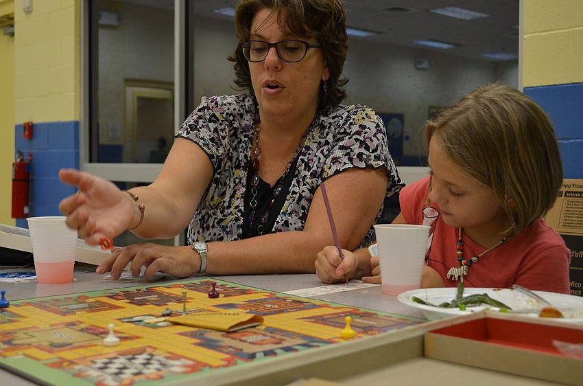 Lori Brosseau and her daughter Ella,9, take turns playing the board game Clue.