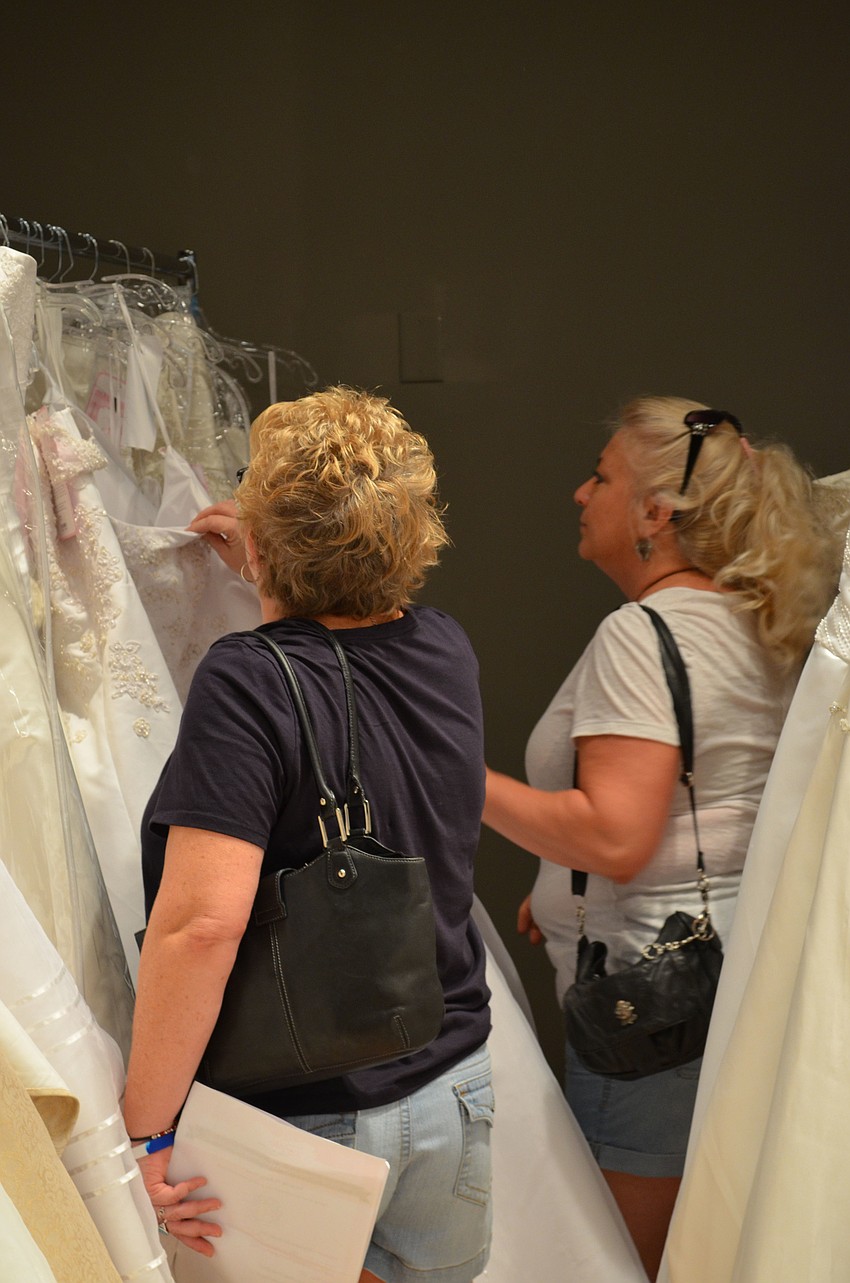 Heidi Dennison and bride, Lisa Schlager browse through the more than 600 gowns that were donated for the bridal show.