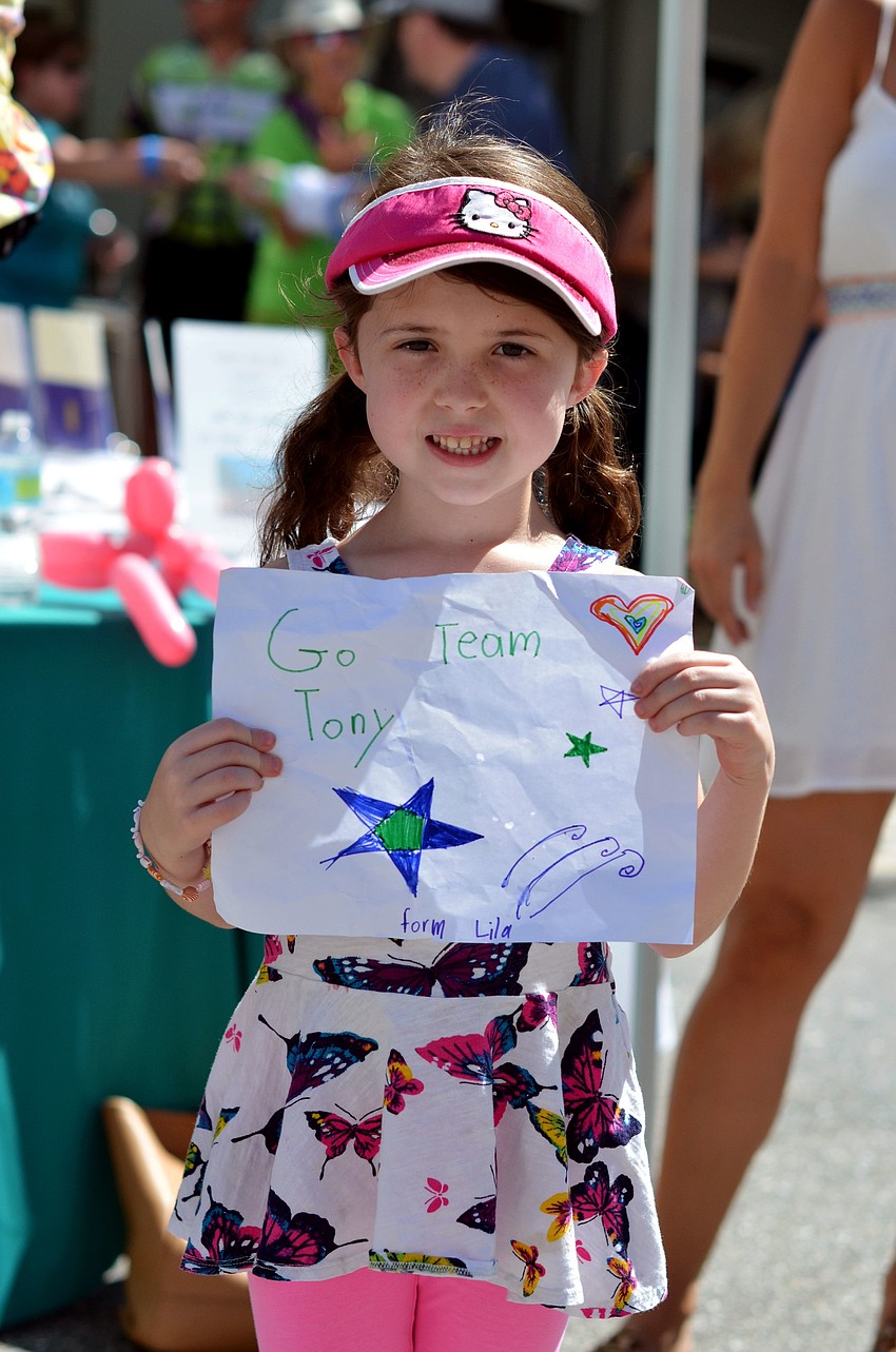 Lila Mertzlufft holding a sign she made to welcome her dad and the other riders in Team Tonyâ€™s 5th annual Cycle of Life at the finish line.