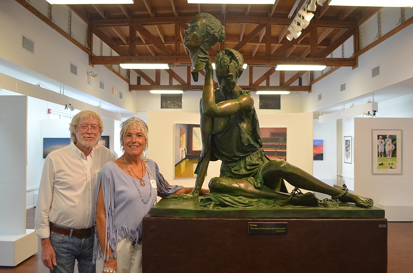 Ed Miracle and partner Tree Beesong pose in front of Miracleâ€™s sculpture â€œTrilogy.â€