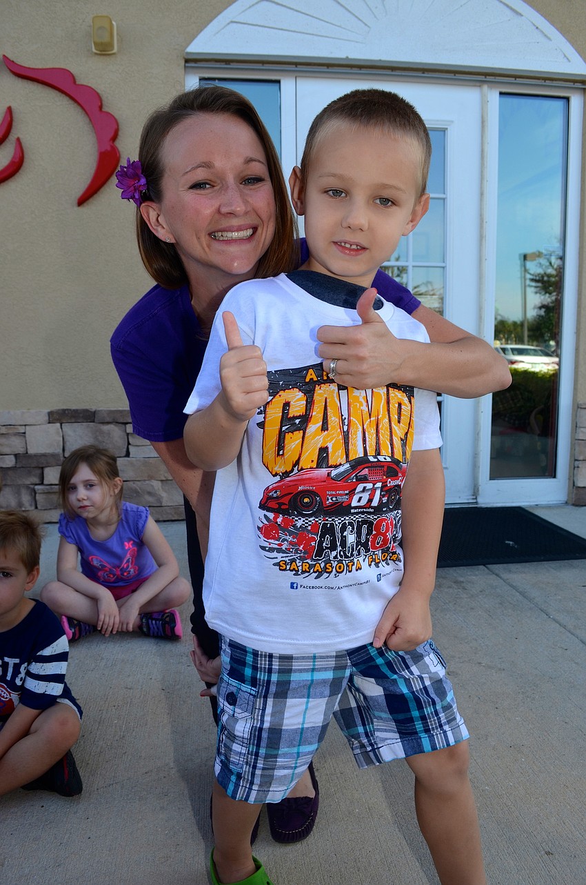 Sarah Parker smiles beside Ben Huff after he tours the inside of a race car.