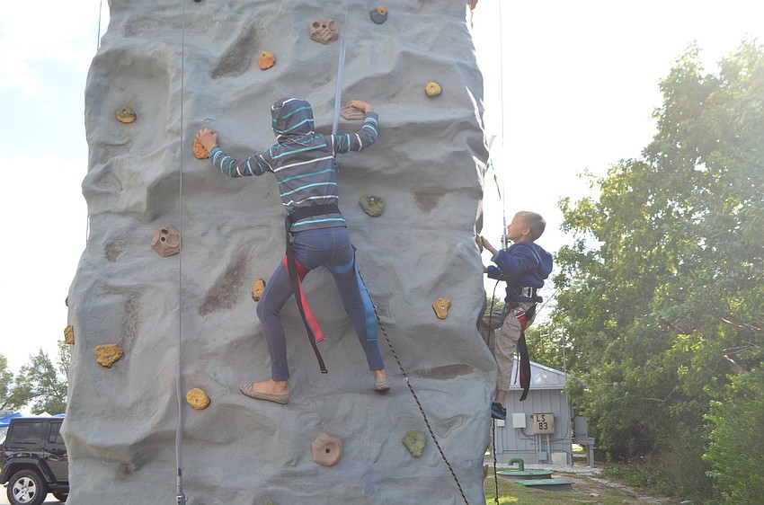 Kelsea and Luke Adams climb the rock wall at the entrance of the festival