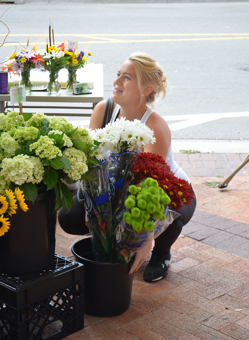 Ellie Bein picks up some flowers from Suncoast Florist Wednesday morning at the Downtown Farmers Market.
