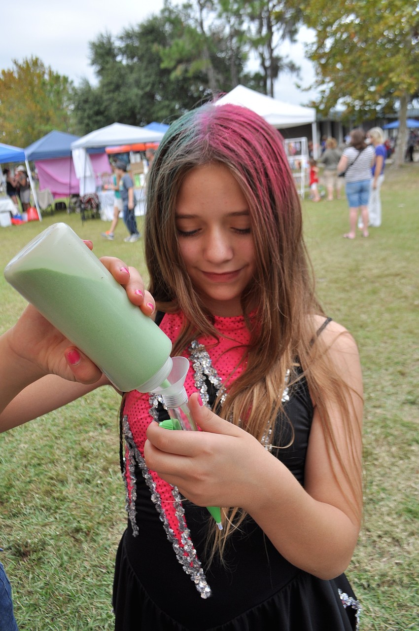 Christina Beaver, 10, adds colored sand to a sand-art pencil.