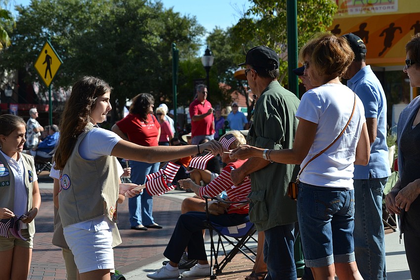 Haven Krizen passes out flags for parade supporters with her Girl Scout troupe.