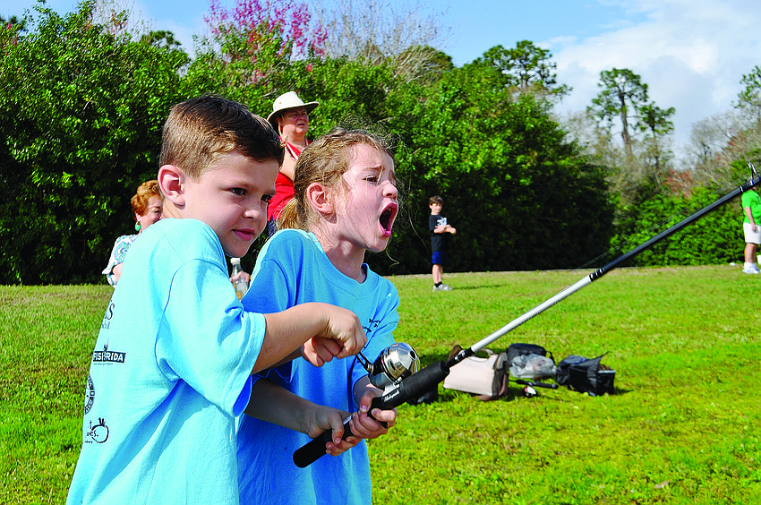 Nico Juliano helps his sister, Bella, reel in her second catch of the day at a Summerfield Lake fishing tournament.