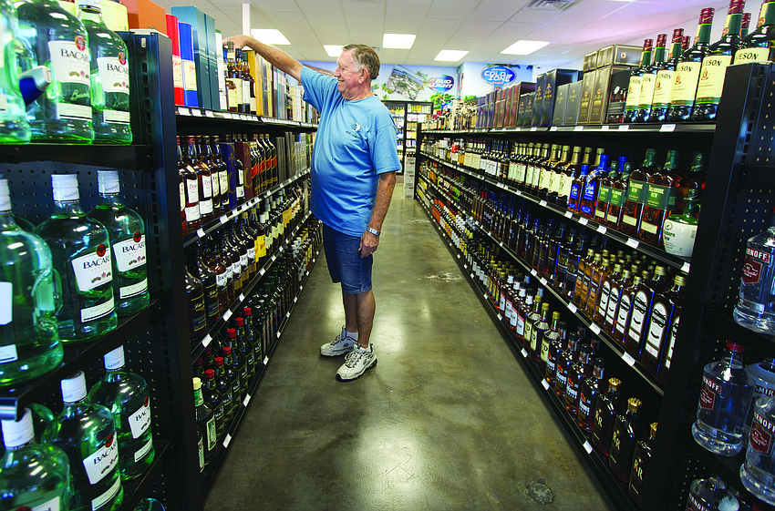Jim Crawford helps stock whiskey and other liquors June 30, at the newly opened LBK Liquors in Whitney Beach Plaza.
