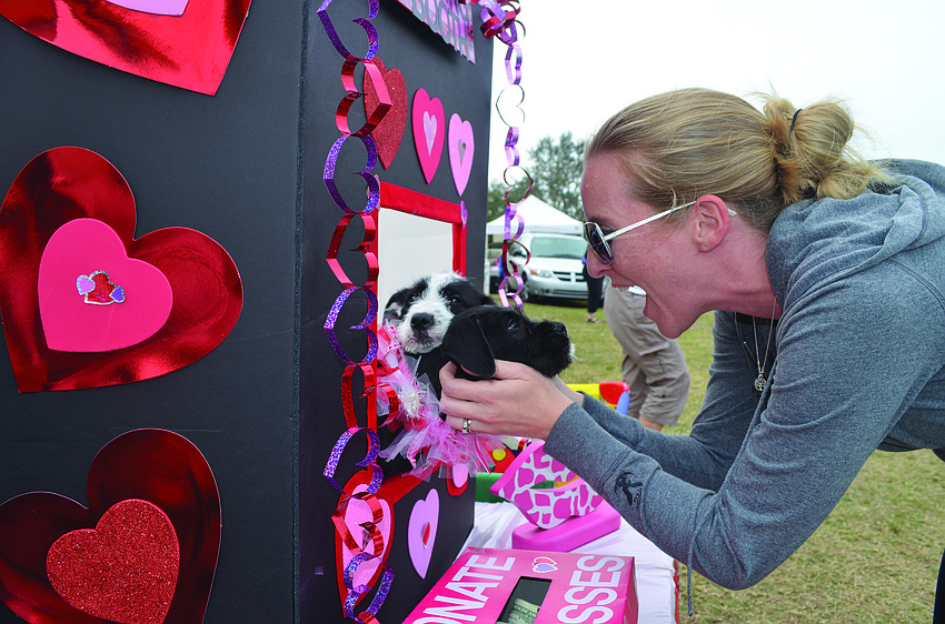 Sara Smith shares the love with a puppy at the The Humane Society of Sarasota County's kissing booth at the Phillippi Farmhouse Market.