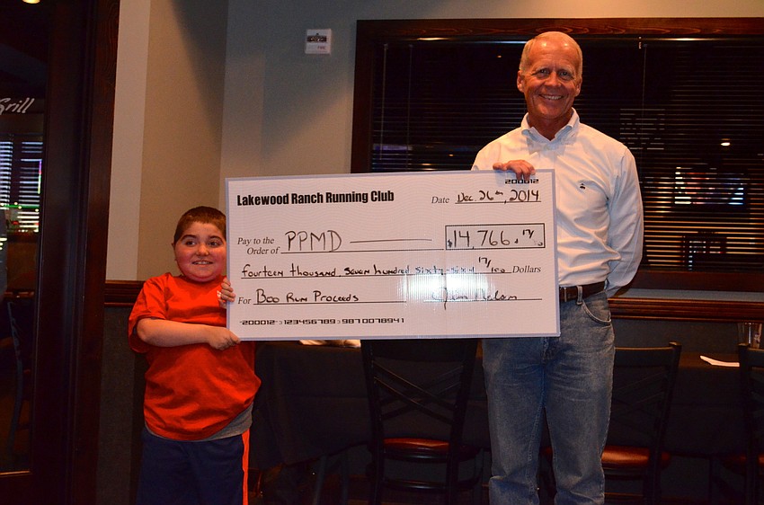 Grayson Tullio and club treasurer Jim Nelson show off the check, which benefits Parent Project Muscular Dystrophy.