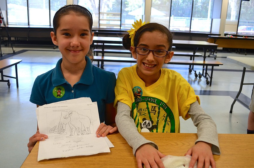 Nine-year-olds Kiara Obando and Yolis Gonzalez show a sketch of the animal they recreated with fruit.