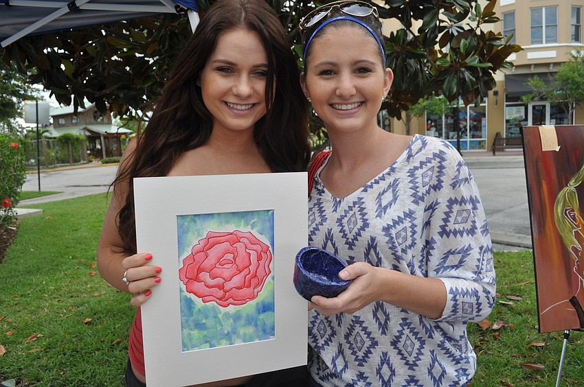Junior Caitlin Curry with Cecilia Smalley, a junior who created a flower with watercolor and also made a pottery piece.