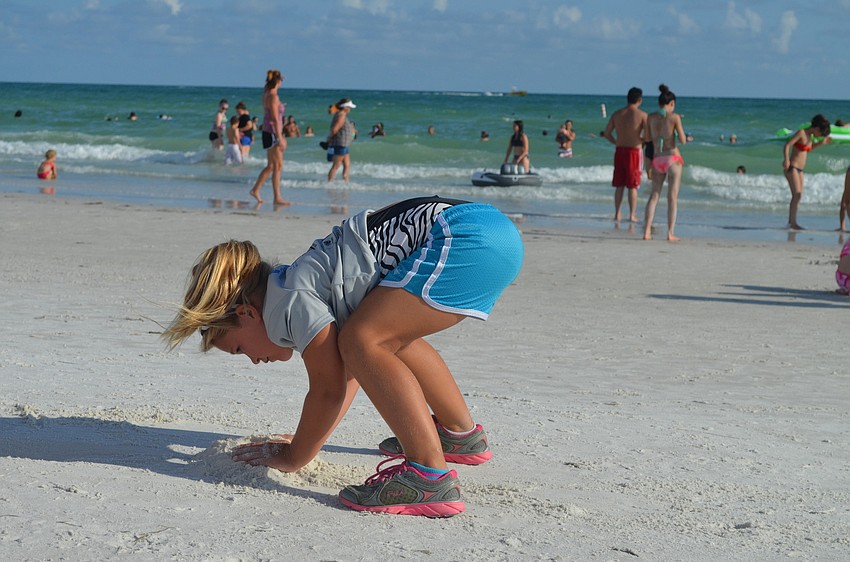 Mary Cates digs in the sand while stretching.