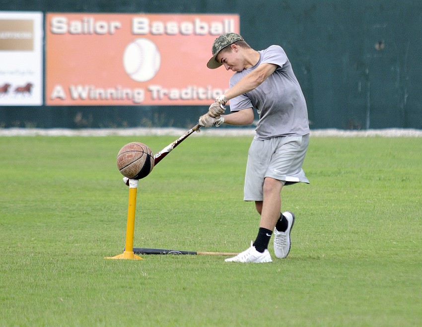 Booker High sophomore Berry Holland works on his swing while hitting a basketball off a tee.