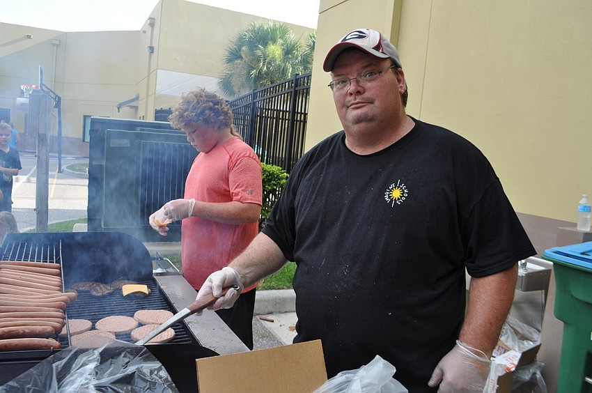 Head custodian Jim Wilson dishes up hamburgers and hot dogs.
