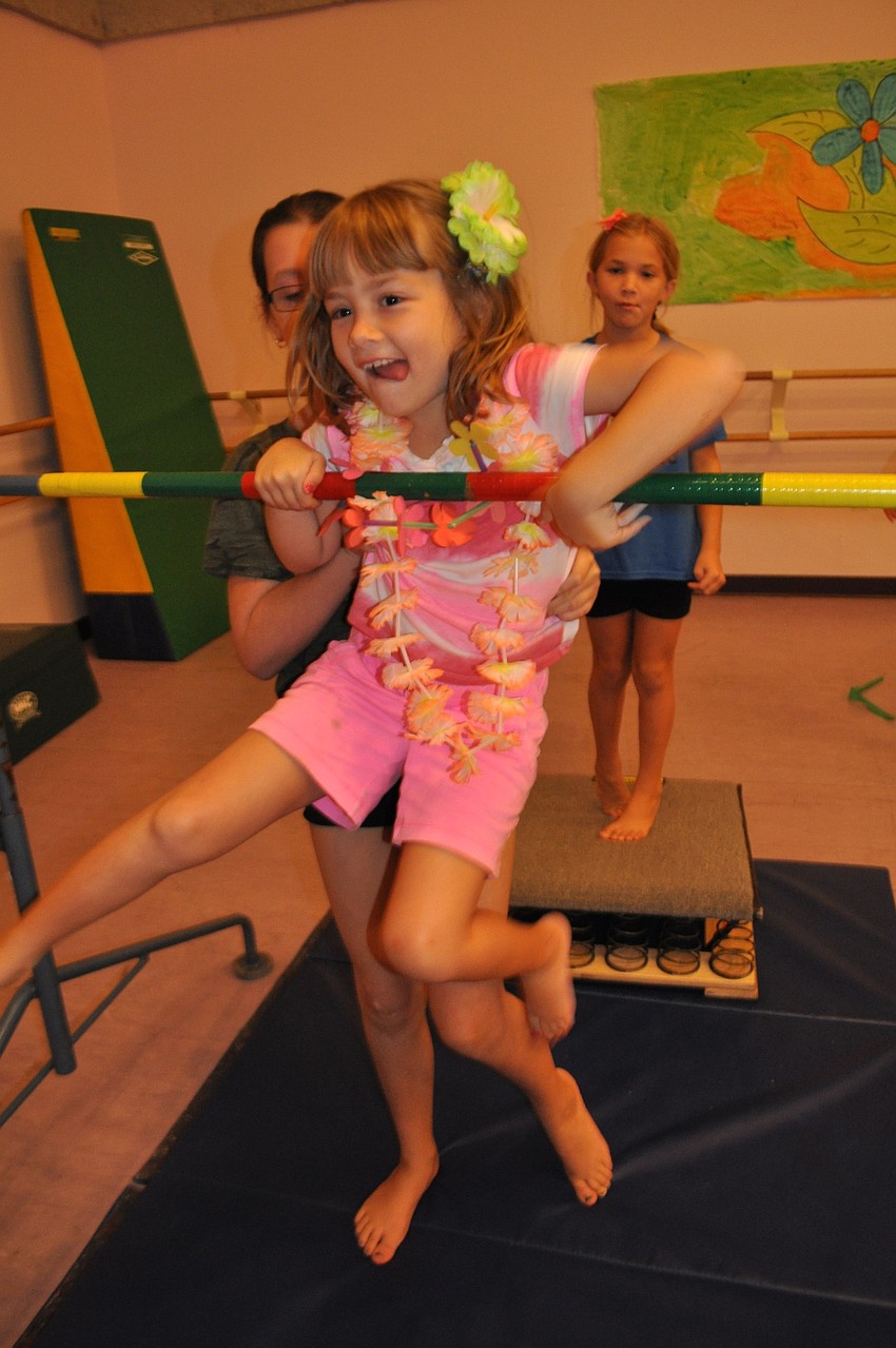 Kelsey Cavanaugh, behind, helps 7-year-old Megan Moletto complete a stint on the bar.