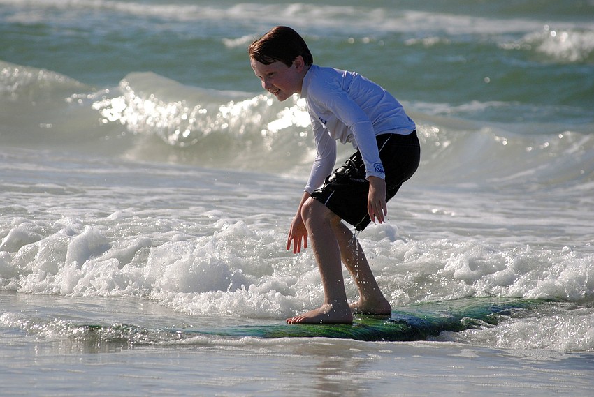 A young surfer catches a wave.