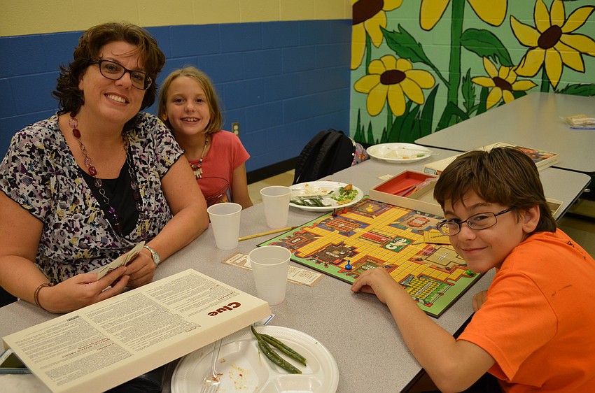 Lori Brosseau, Ella, 9, and Michael, 11, review the rules for the game Clue.