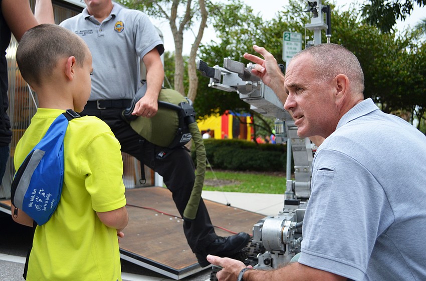 Sgt. Bryan Graham of the Explosives Materials Unit explains the uses for a robot to Payton Barnes.