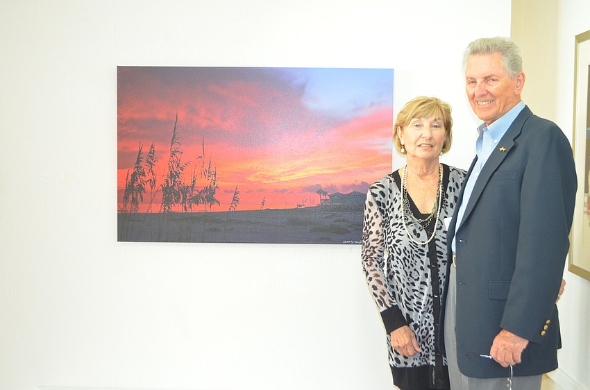 Ron Johnson and wife Jinny pose in front of Johnsonâ€™s photograph â€œThe Dayâ€™s Grand Finale.â€