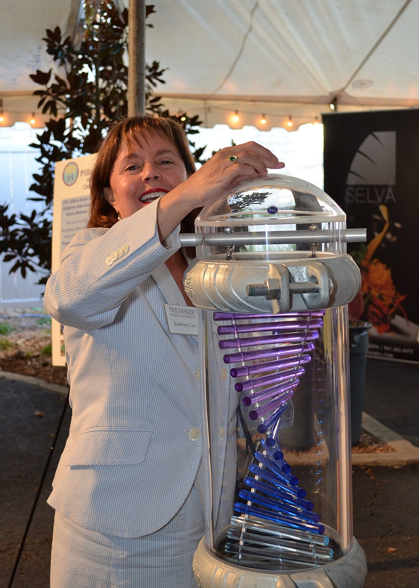 Kathryn Carr adds two marbles to the pillar for her donations to the Child Protection Center.