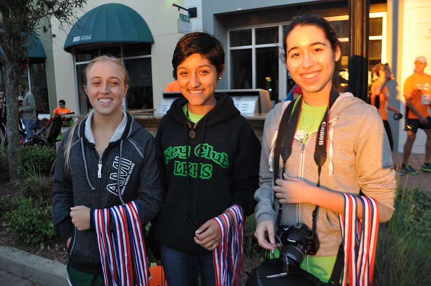 Kyra Senchyshak, Haydee Alonso and Arianna Rodriguez pass out medals after the kids' dashes.