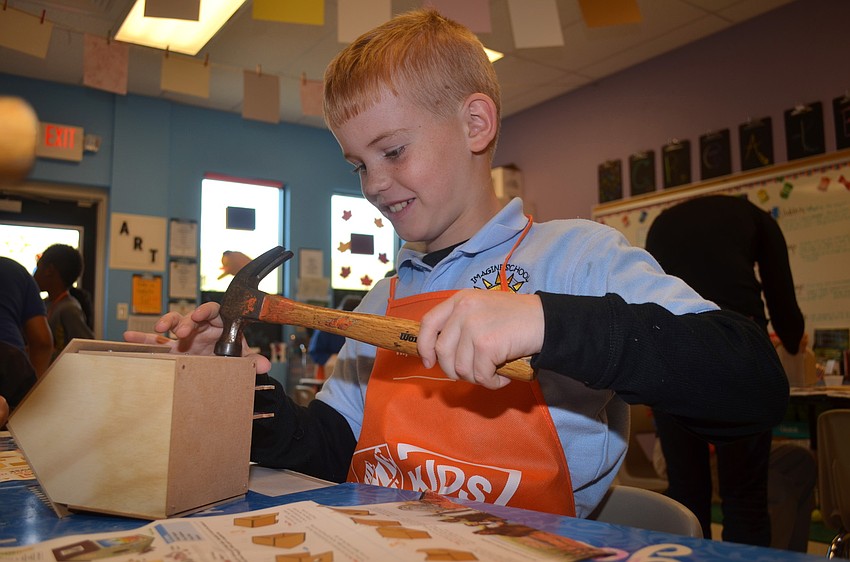 Dustin Preyer hammers the nails into his wooden house.