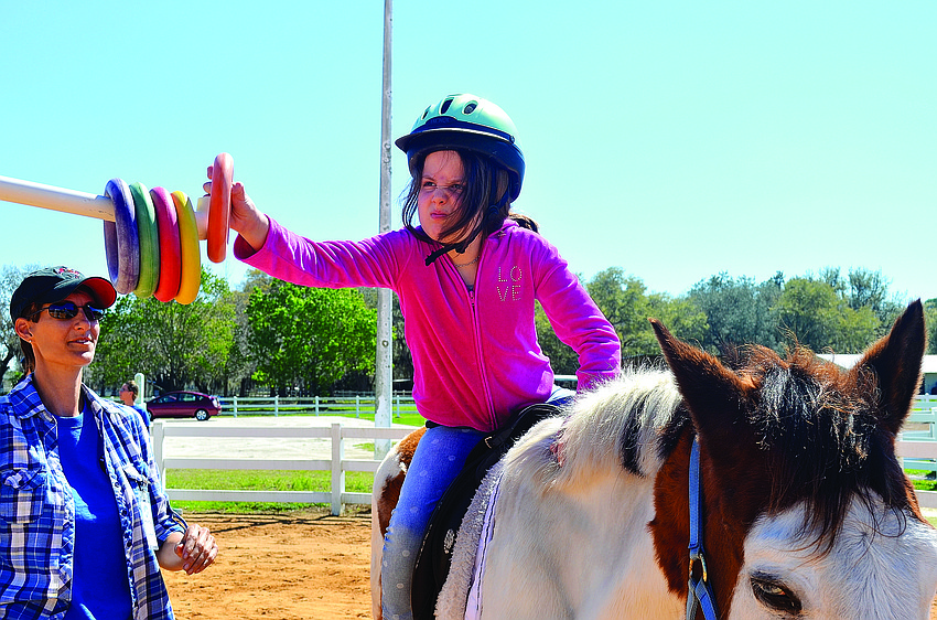 Nine-year-old Iza Ramsey works to improve her flexibility Feb. 28, at the Sarasota-Manatee Association for Riding Therapy's arena.