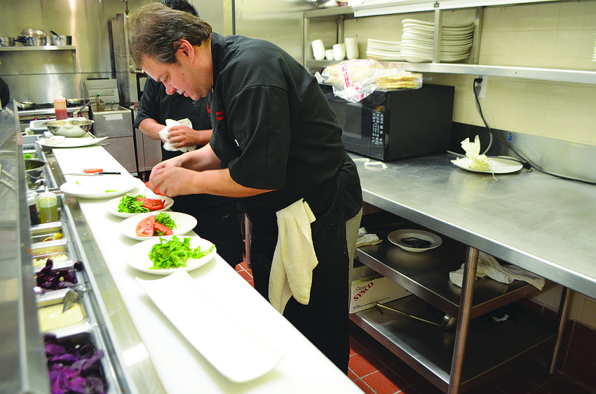 Executive chef Andrea Bozzolo creates a salad with arugula, tomatoes and shaved Parmesan cheese during the opening night Nov. 13, of Amore by Andrea.