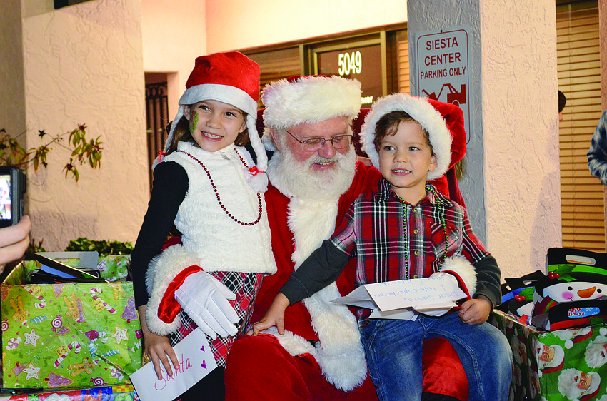Jadynn Bachman and her brother, Jonathan, tell Santa Claus what they want for Christmas at the Light up the Village holiday parade on Siesta Key. 4
