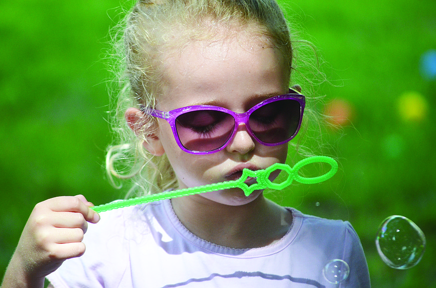 Gia Huff blows bubbles at Selby Gardens' Super Saturday event.
