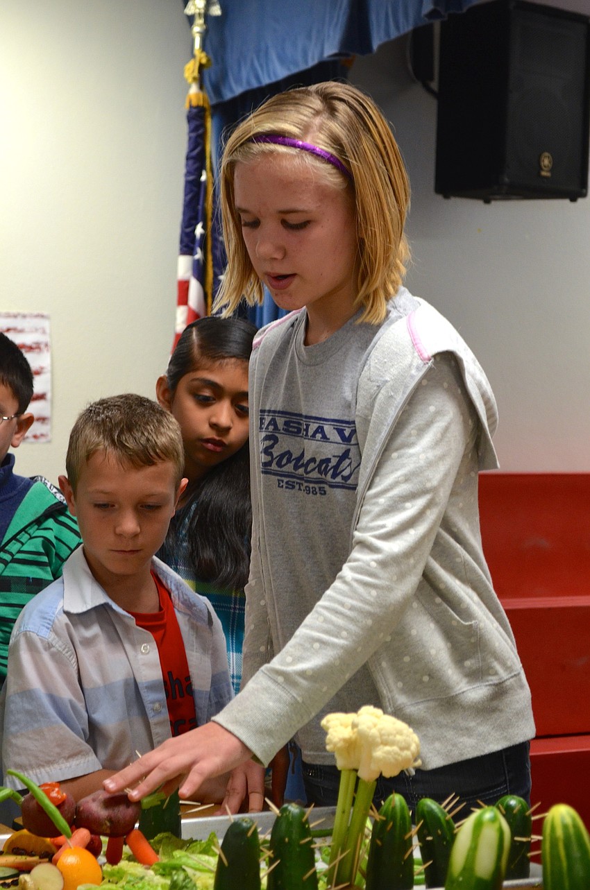 Zoe Cummings explains the cucumber lake and toothpick and cucumber cacti her team crafted.