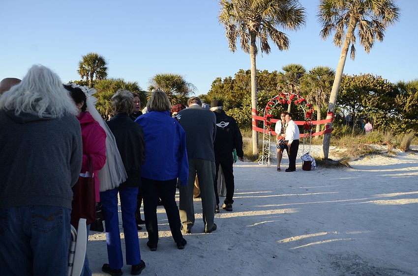 Couples line up to snap a photo under the rose-covered arches.