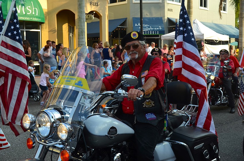 Veteran Butch McIntyr rides his motorcycle for a cheering crowd.