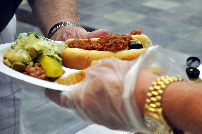 Volunteers help prep dinner plates in the buffet line at St. Mary Menâ€™s Clubâ€™s Hot Dog Cookout.