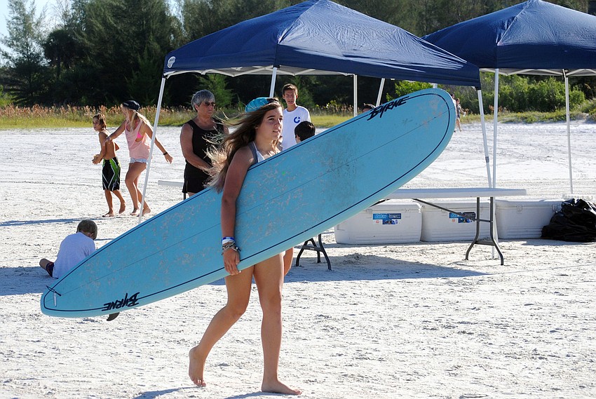 A young surfer carries her board to the water.