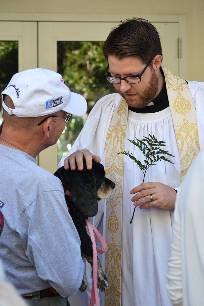 Father Ralph Strohm holds cocker spaniel Meg to be blessed by Rev. David Bumsted.