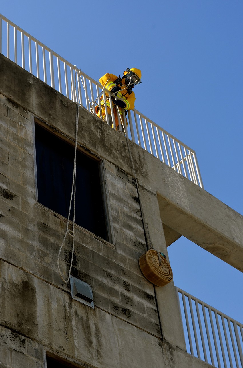 Trevor Porter pulls a hose up a multi-story building.