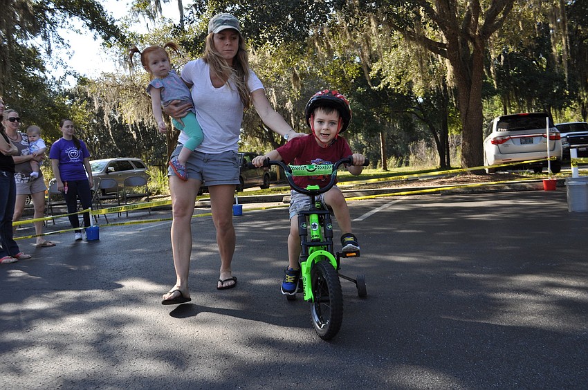 Rachel Wiedeman, holding Selah, helps her son, Grady, push off.
