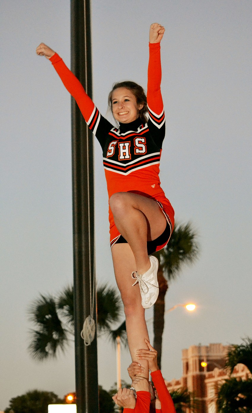 Sarasota High School cheerleader Kelsey Jarrett performs a stunt at the Alumni Tailgating event Friday night.