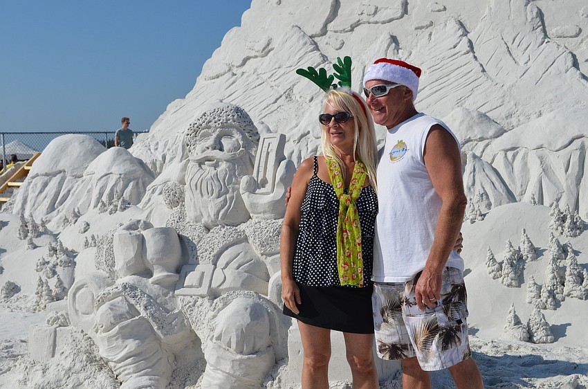Susan and John Dragun pose with a sand sculpture of Santa Claus.