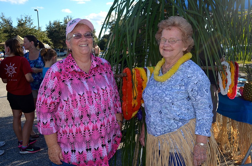 Starla Seth and June Kagy enjoy time in the shade near their Hawaiian-themed booth.
