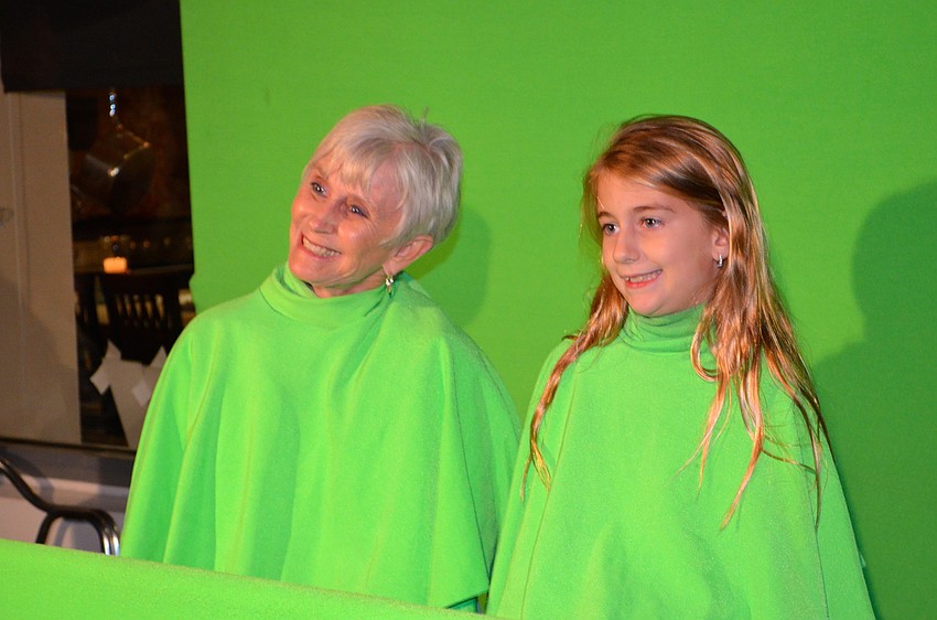 Val Grimwood and her granddaughter, Aubrey, sit in front of a green screen for a simulated dance routine.