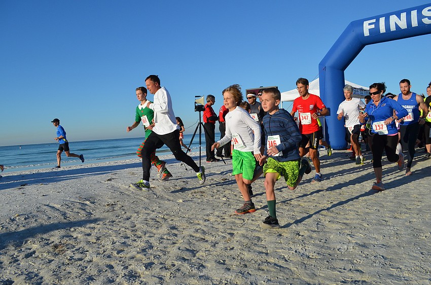 Runners take off down the beach for the 5K portion of the Sandy Claws Beach Run.