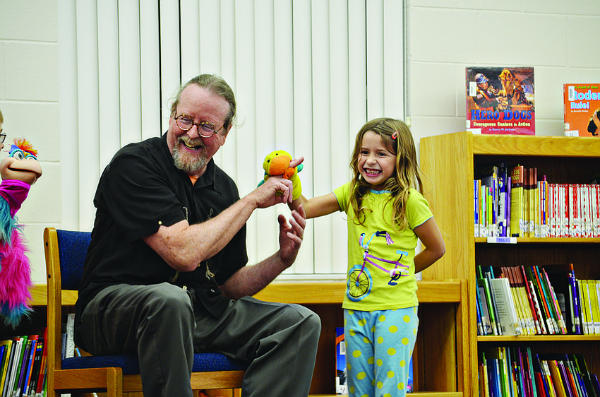 Addison Trembley helps Bill Codell tell a story at Phillippi Shores Elementary School.