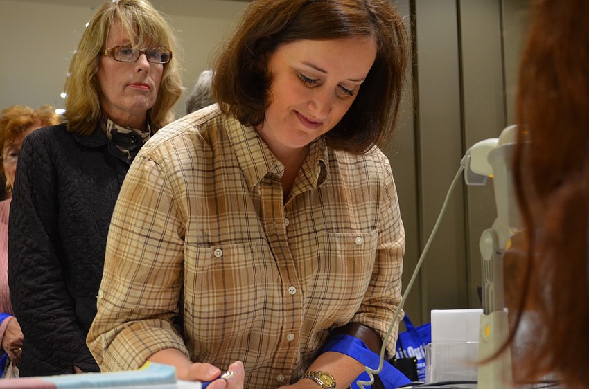 Pam Fetty fills out the form for a new library card at the front desk.
