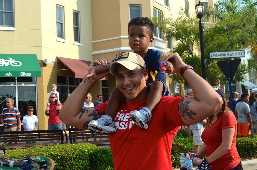 Steve Garcia carries Elijah Joseph on his shoulders as they walk in the parade.