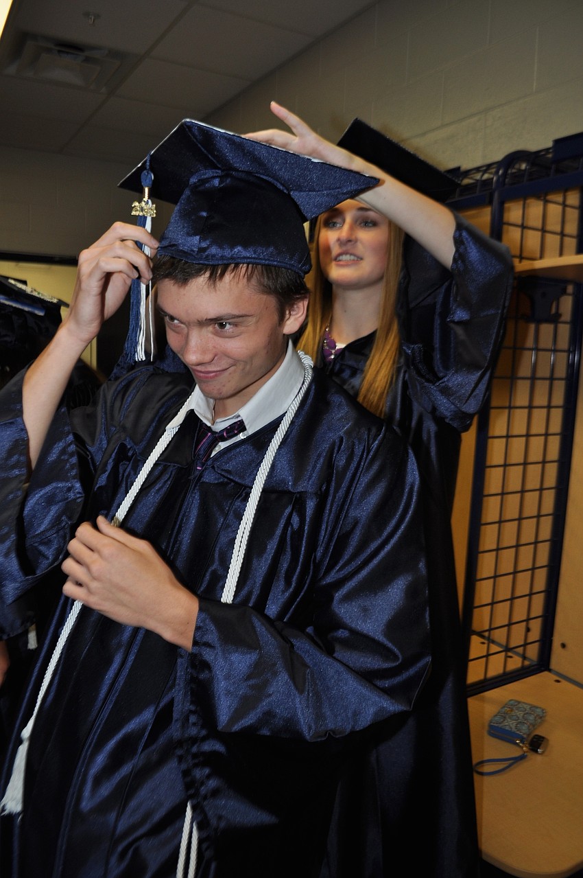 Emma Holland, right, helps Peter Runge put on his cap.
