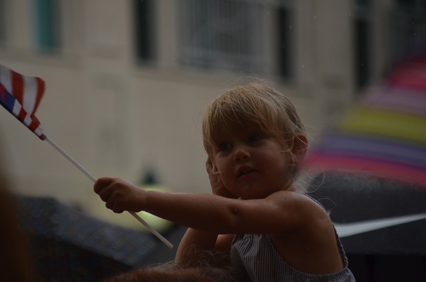 Ava Harms waves a flag as she covers her ears from the horns.